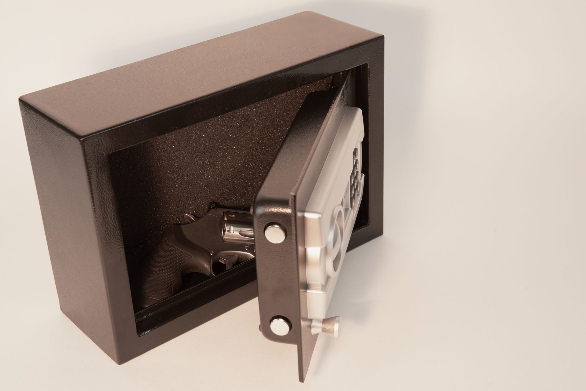 Black safe with open door on a white surface, revealing a dark interior and locking mechanism.