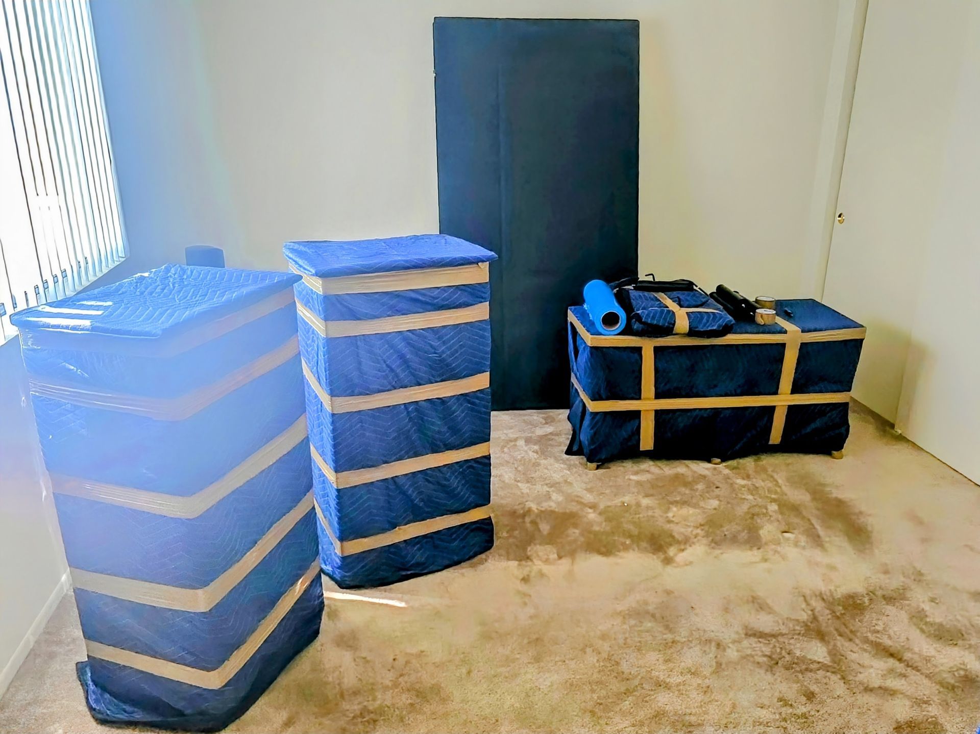 Two people carrying stacked cardboard boxes outside a building.