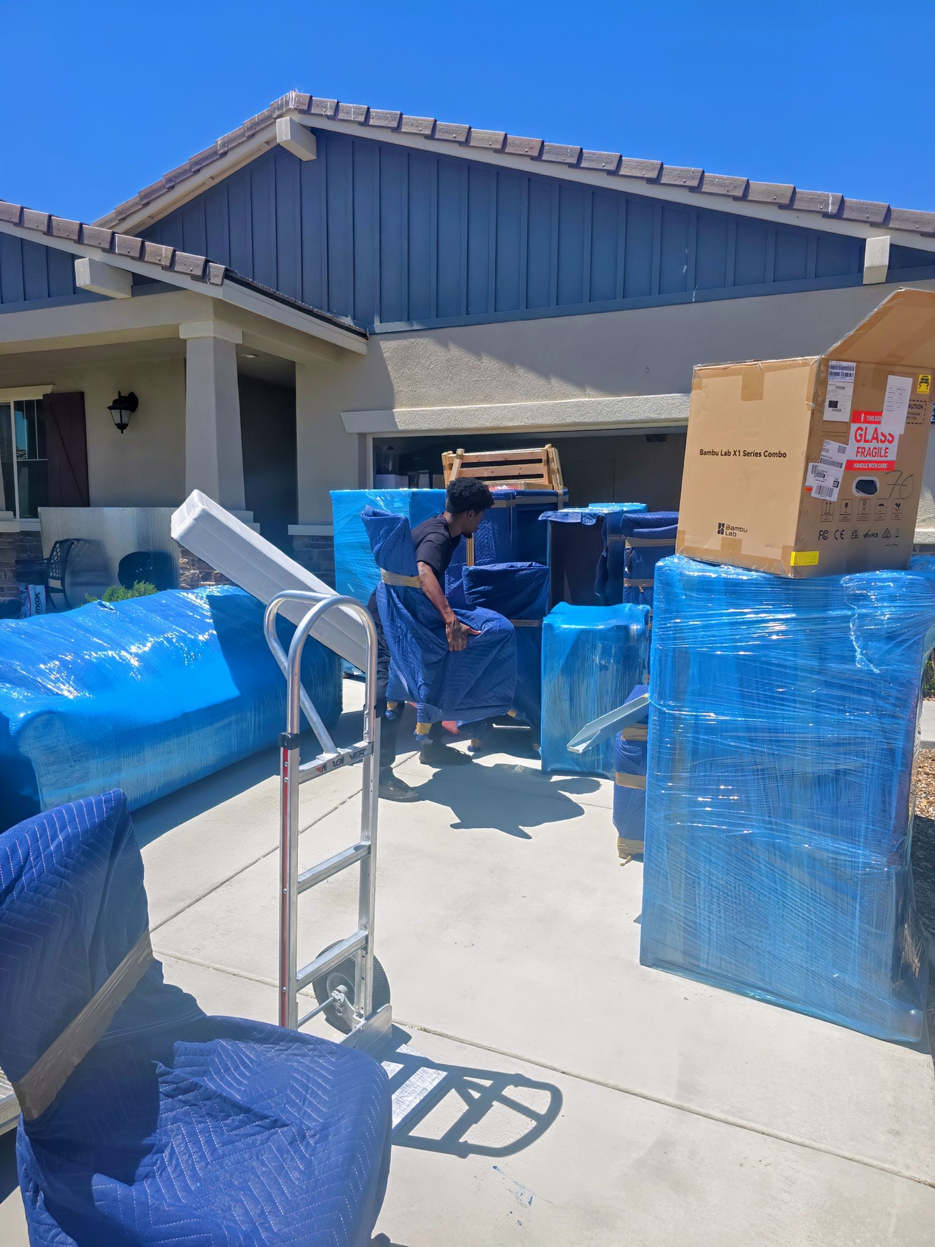 Two men are wrapping a large piece of furniture in plastic wrap.