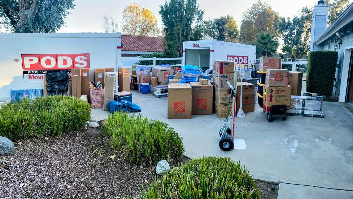 A man is stacking boxes on top of each other in a living room.