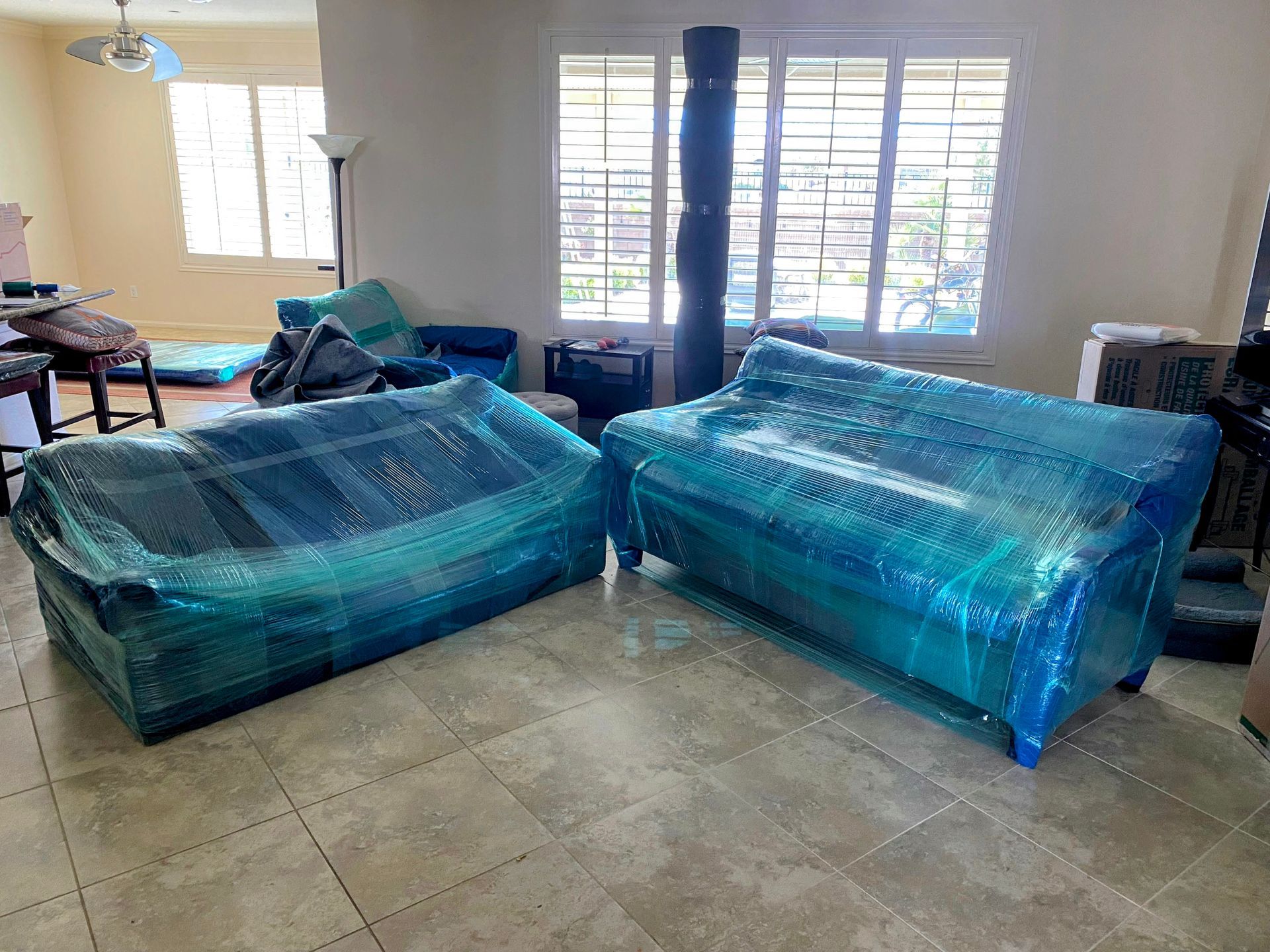 A living room with two couches wrapped in plastic.