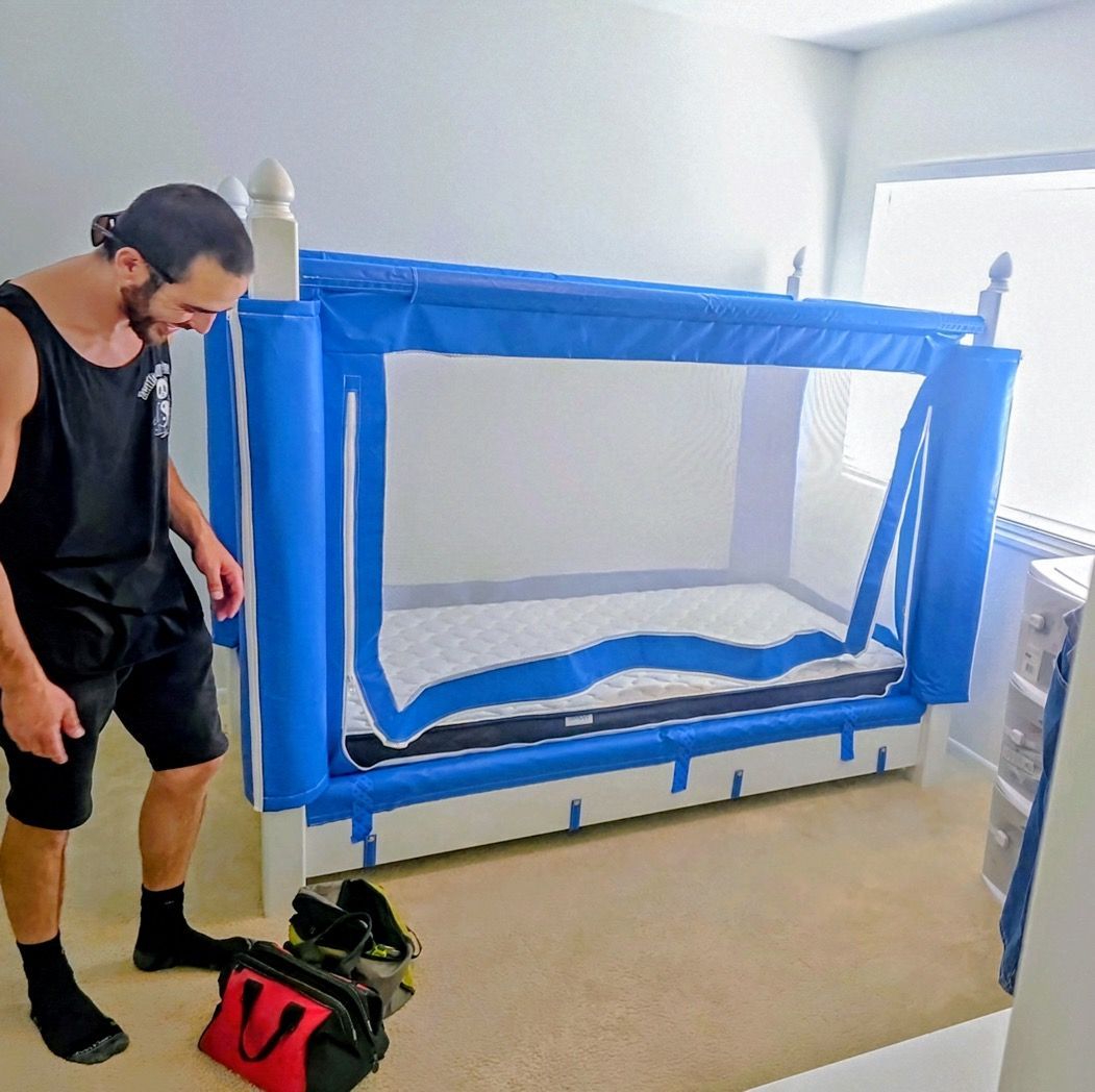 A man is kneeling down to assemble a shelf in a living room.