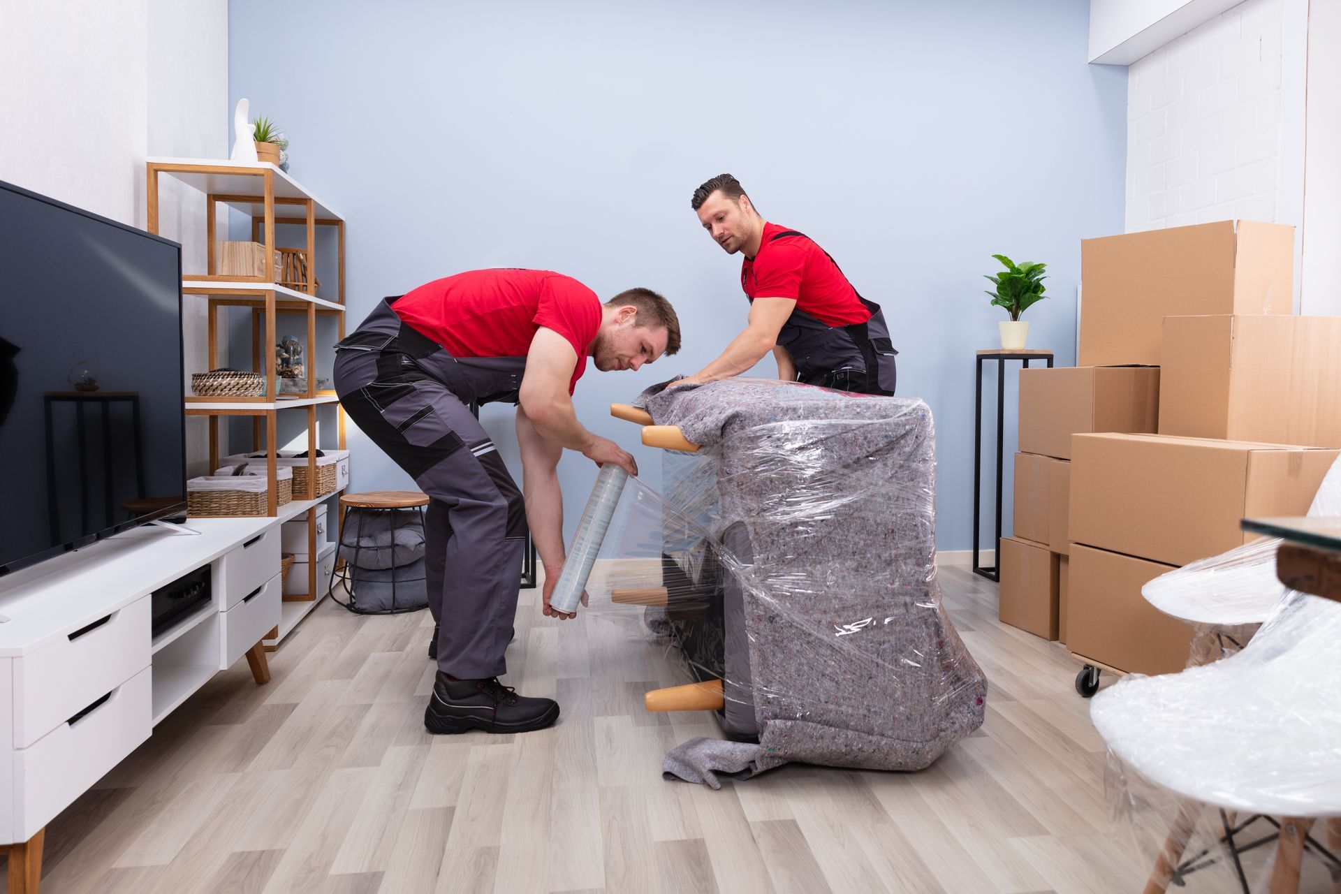 Two men are moving a couch in a living room.