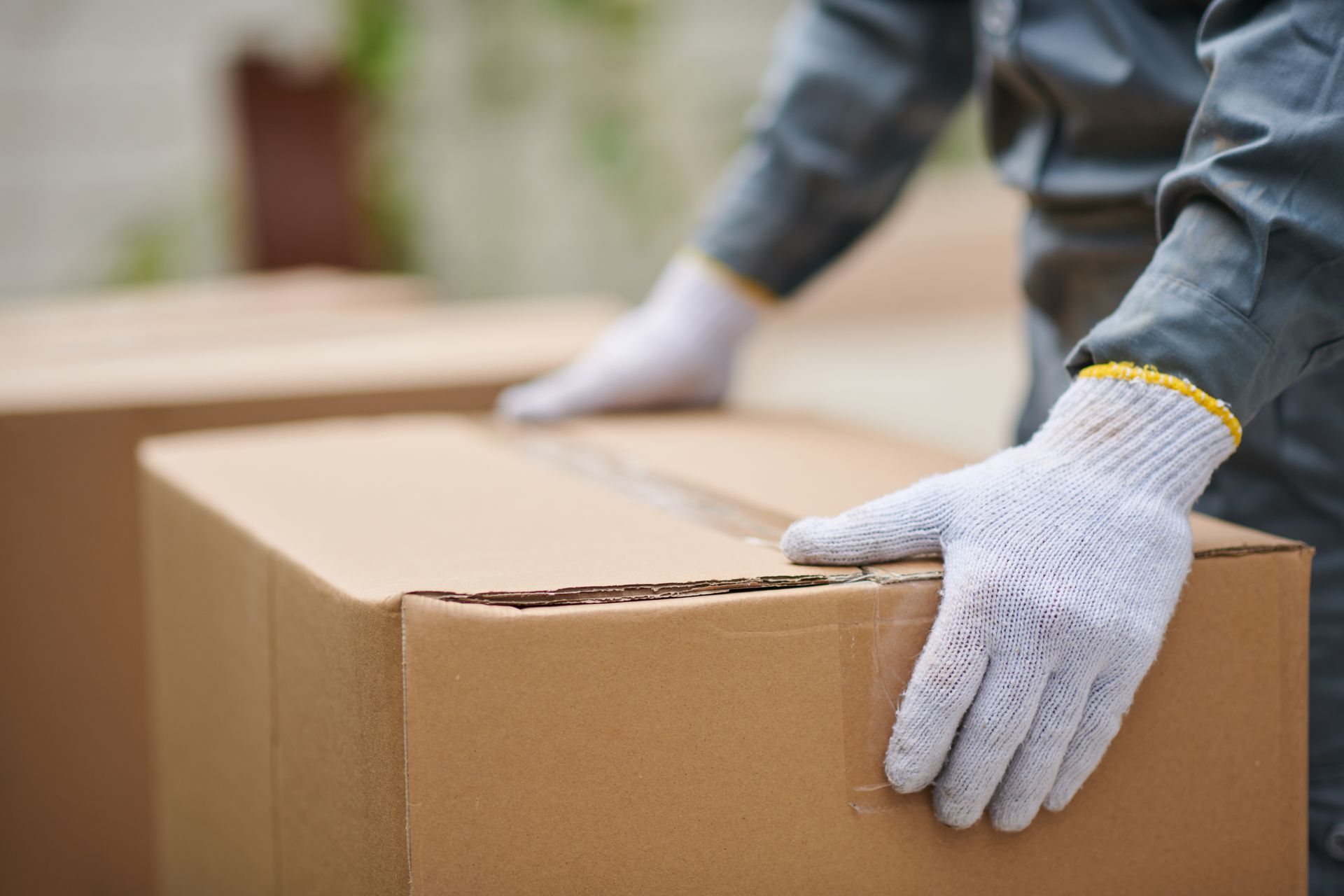 A person wearing white gloves is holding a cardboard box.