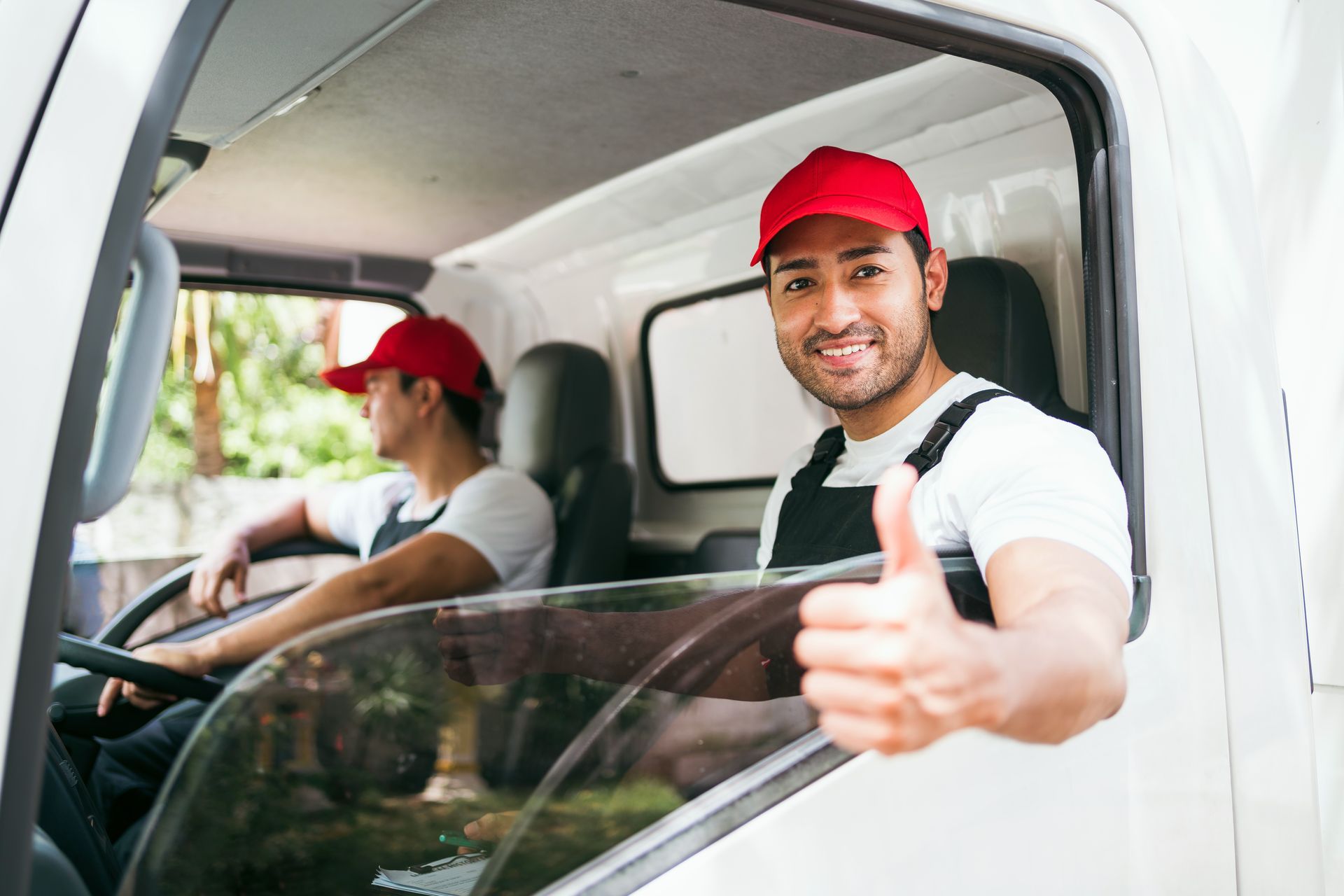 A man is giving a thumbs up while sitting in a truck.