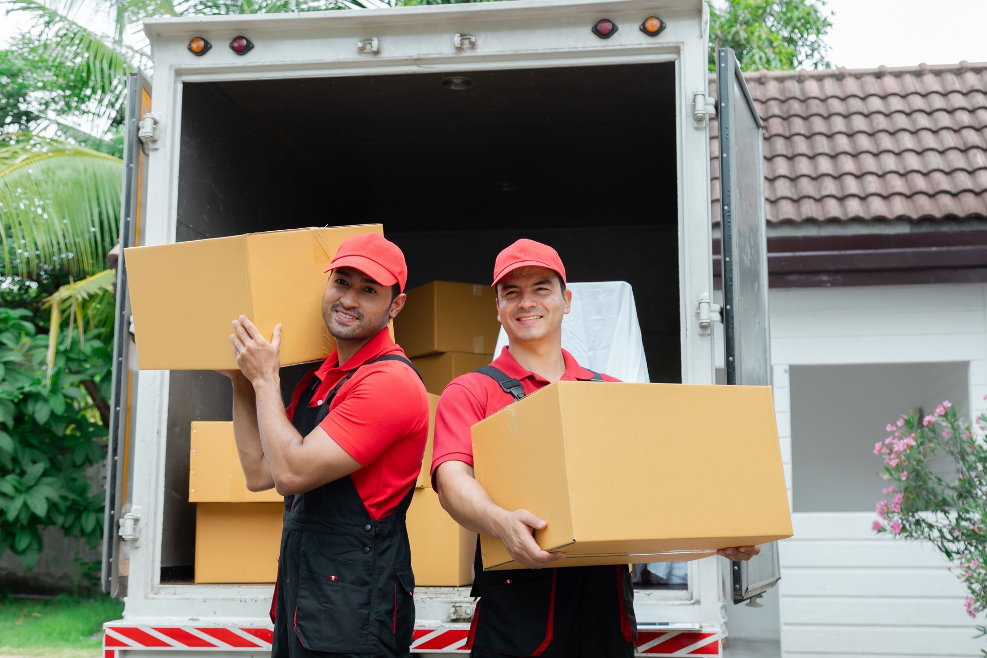 Two men are carrying boxes out of a moving truck.