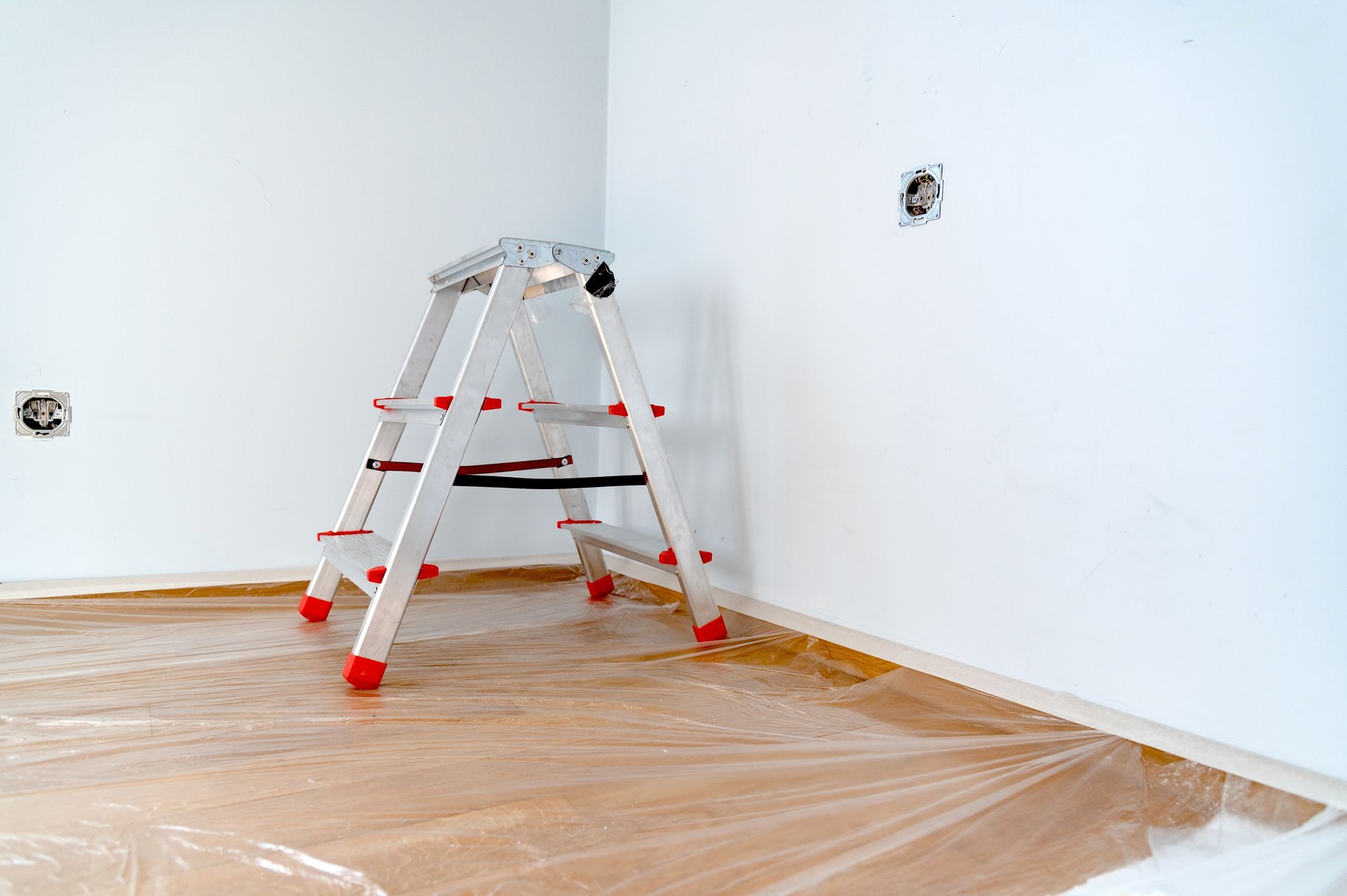 A ladder is sitting on top of a plastic sheet in a room.