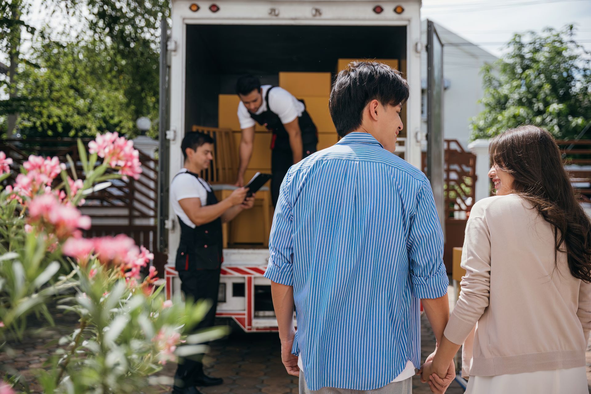 A man and a woman are standing in front of a moving truck.