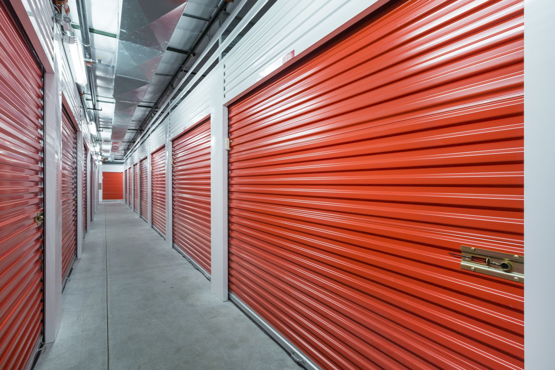 A row of red garage doors in a storage facility.