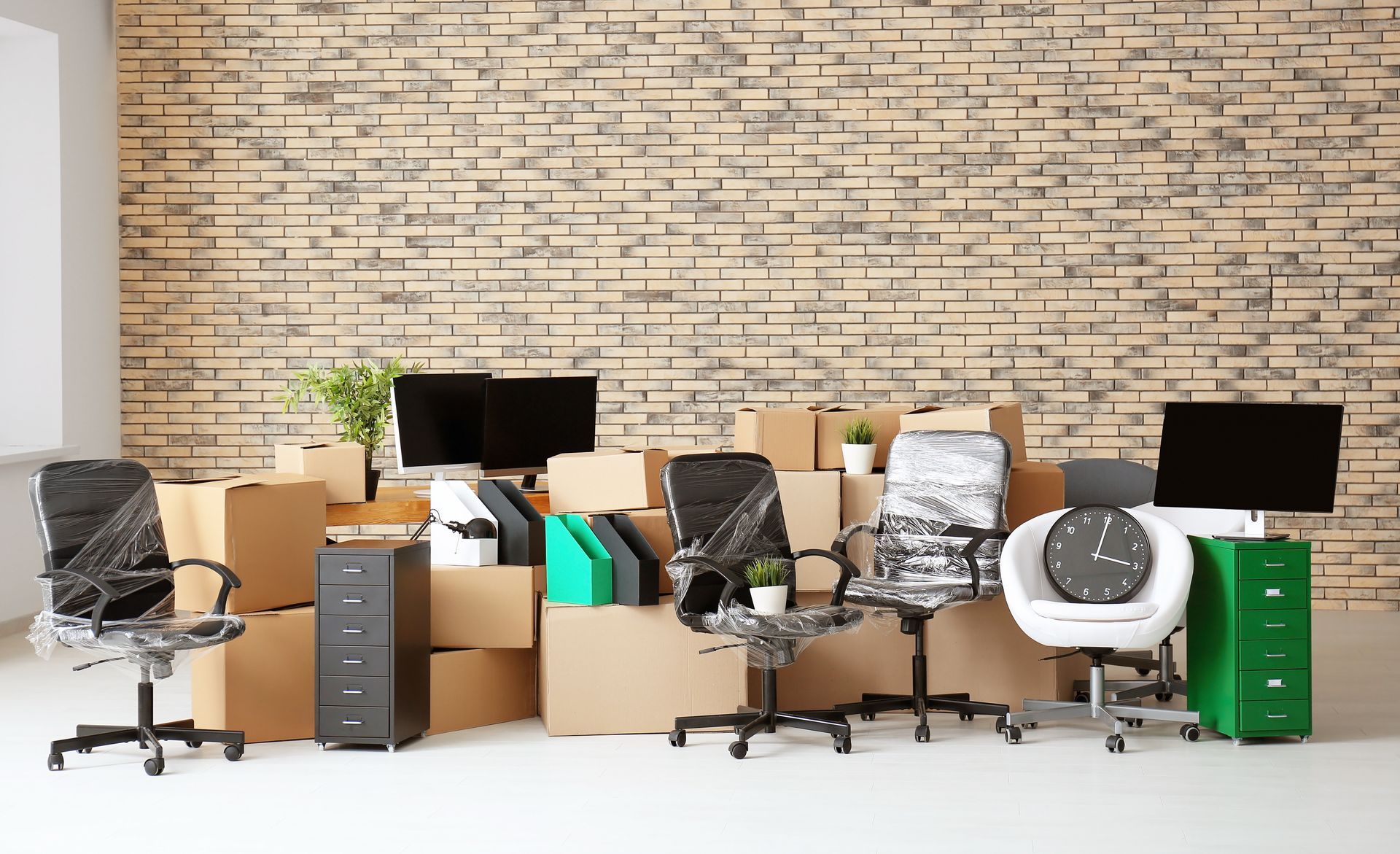 A row of office chairs and boxes in an office with a brick wall.