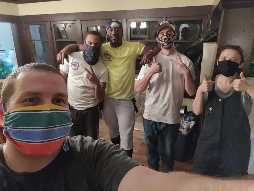 A group of people wearing face masks are posing for a picture.