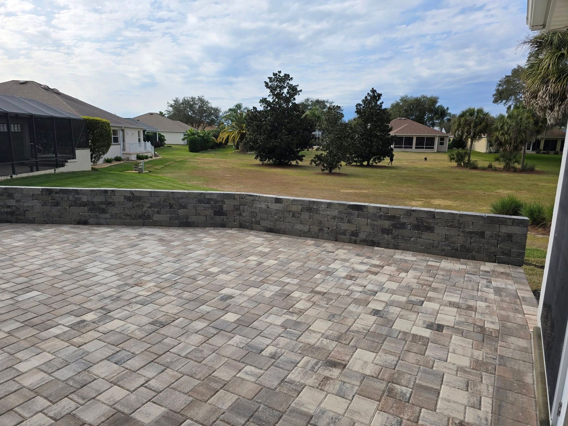 A brick driveway leading to a house with trees in the background