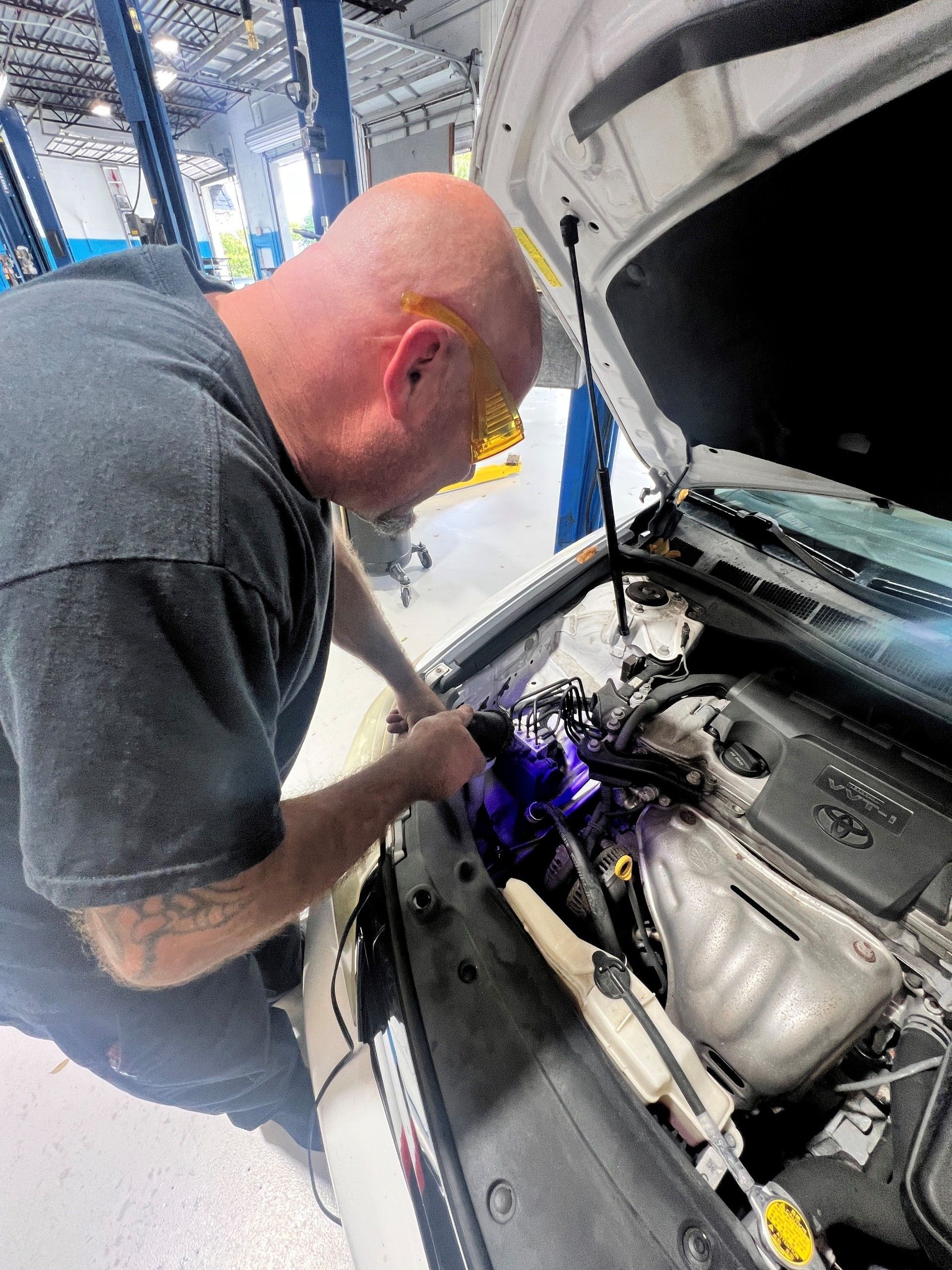 Mechanic inspecting car engine under open hood in a workshop