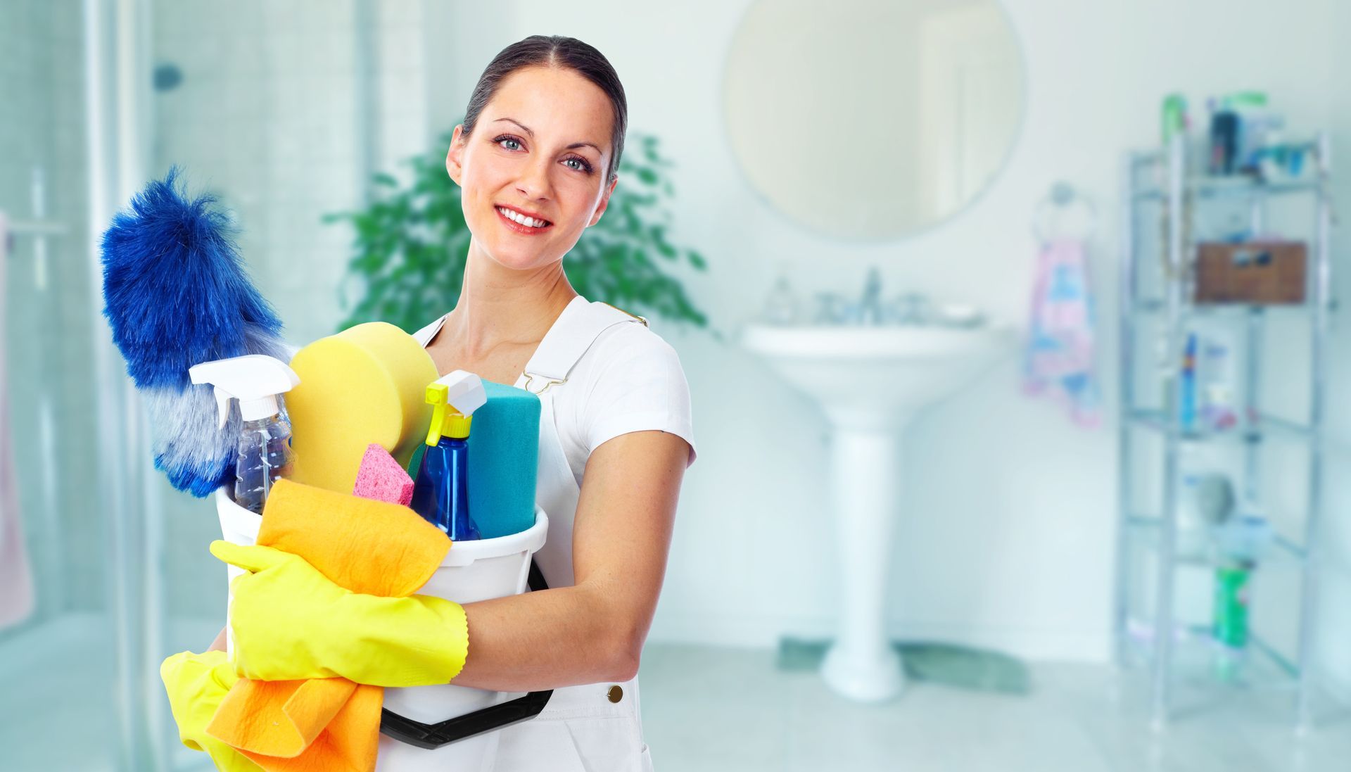 Person holding cleaning supplies and a mop inside a bright room