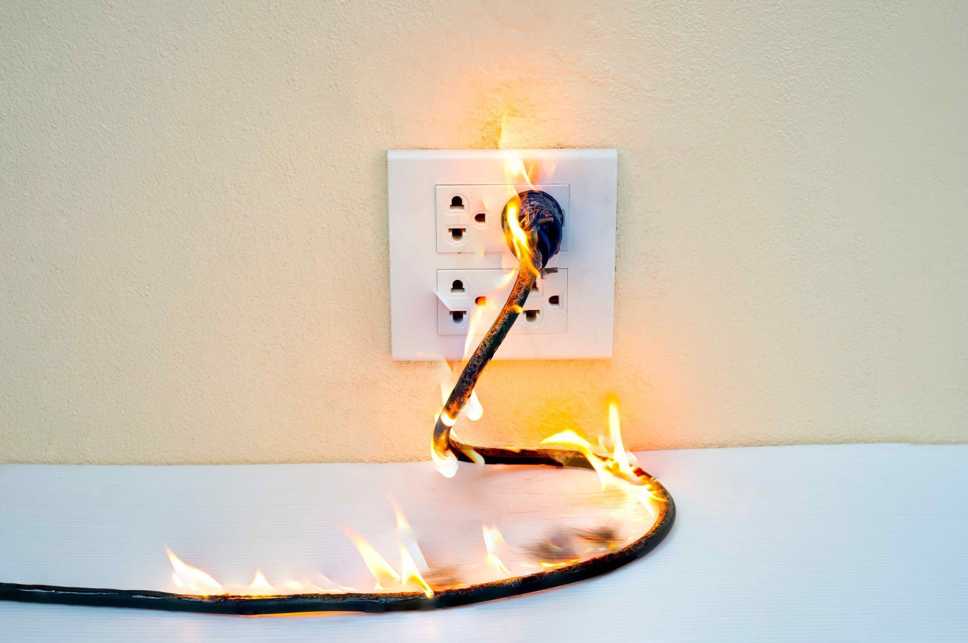 electrical cord plugged into an outlet on fire