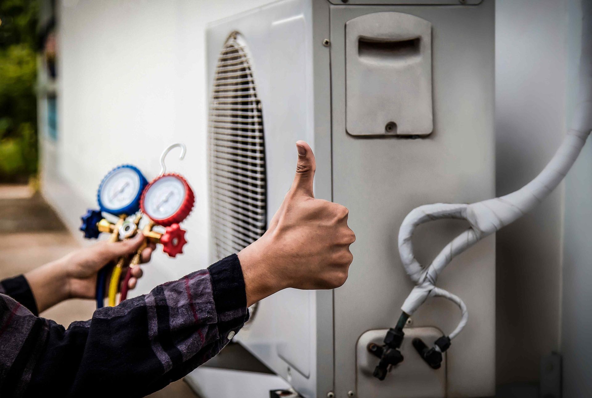 outdoor air conditioner after installation with an electrician's hand giving a  thumbs up in the middle of the picture