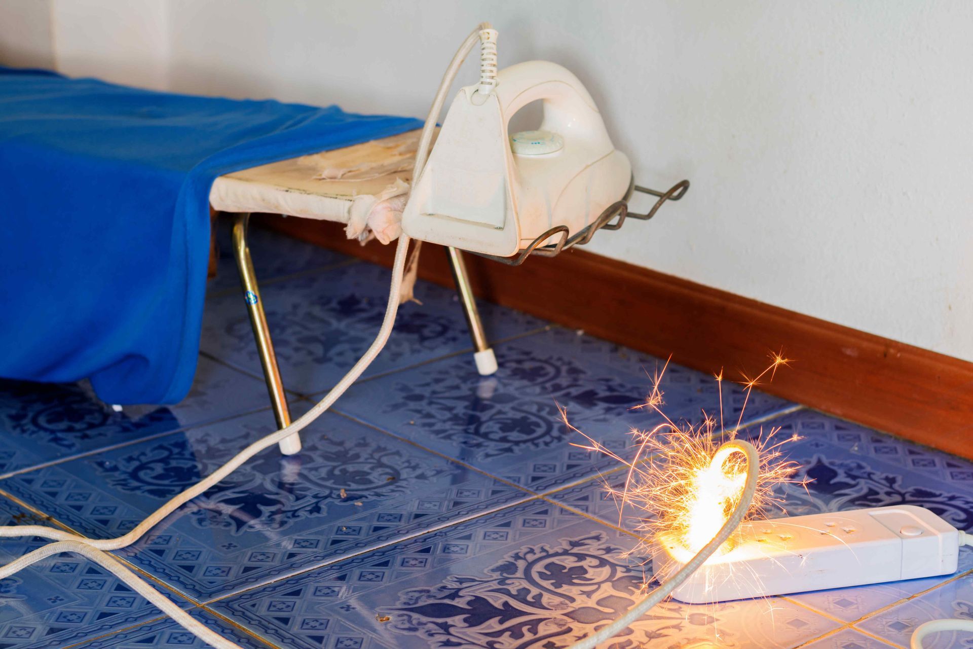 an iron plugged into a surge protector that is sparking and in flames