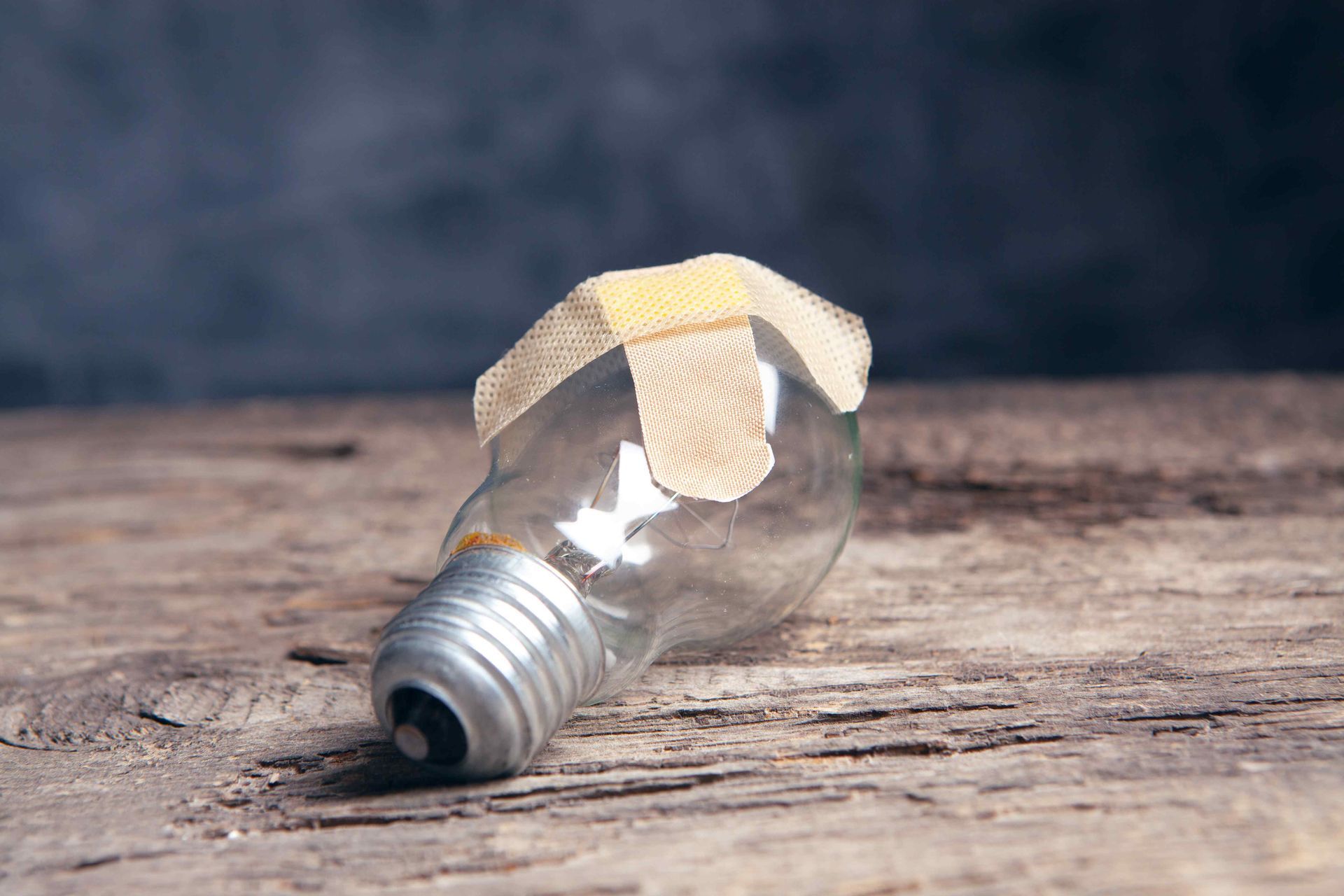 light bulb resting on a wooden table with 2 band aides in an 