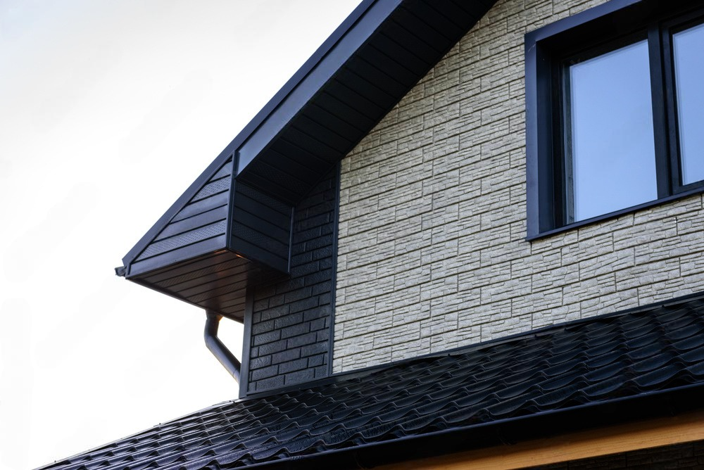 The side of a house with a black roof and a window