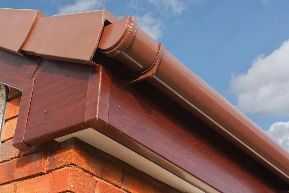 A close up of a brown gutter on a brick building.