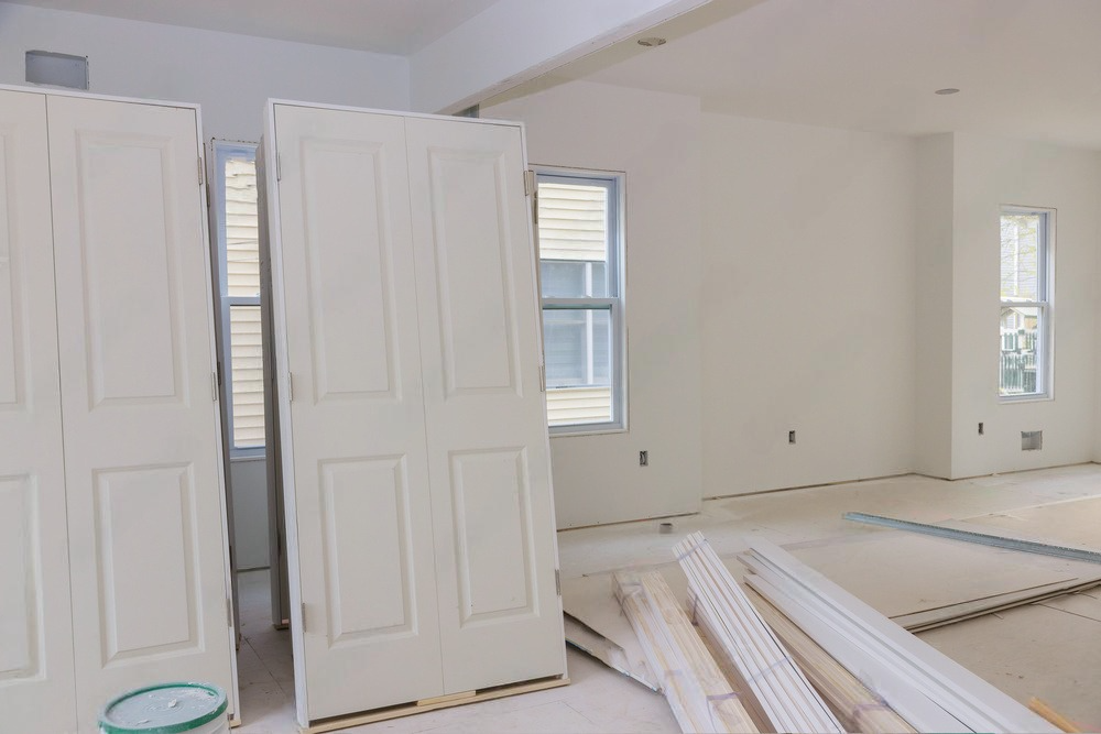A row of white doors are sitting in an empty room.