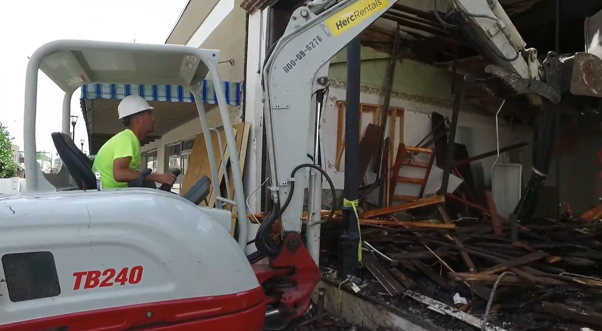 A man is driving a white and red excavator.