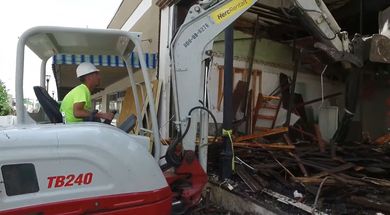 A man is driving a white and red excavator.