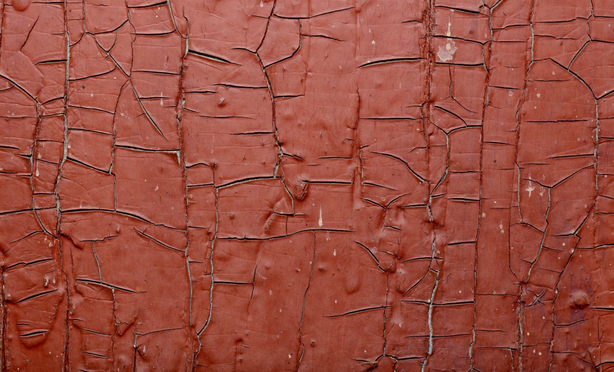 A close up of a red wall with cracks in it