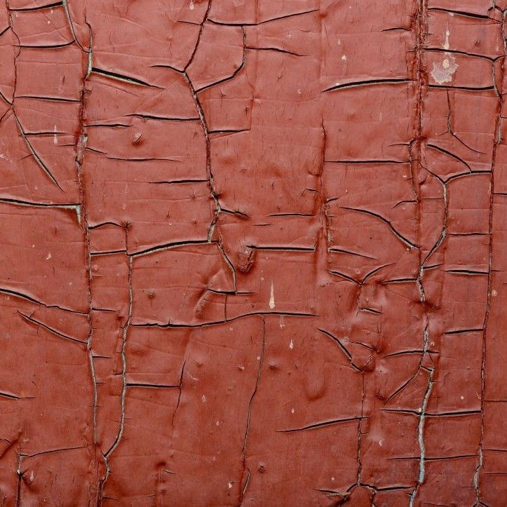 A close up of a red wall with cracked paint