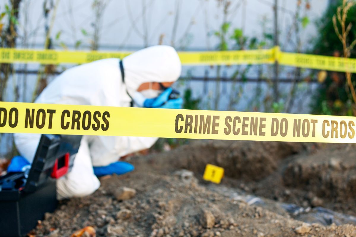 A man in a protective suit is looking at a crime scene.