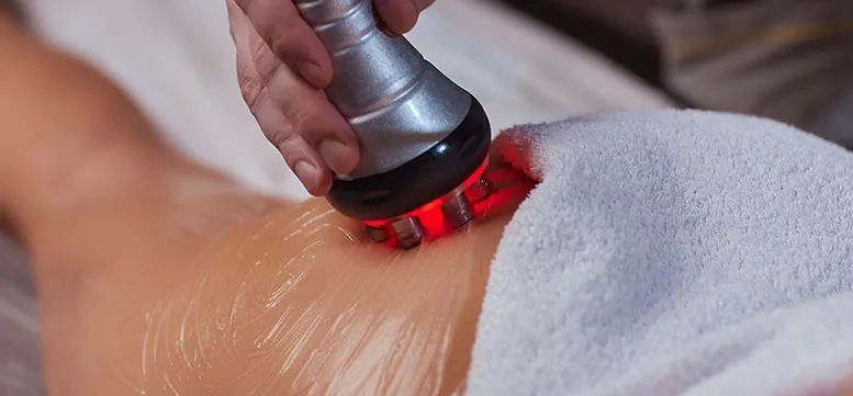 A woman is getting a cavitation treatment on her back.
