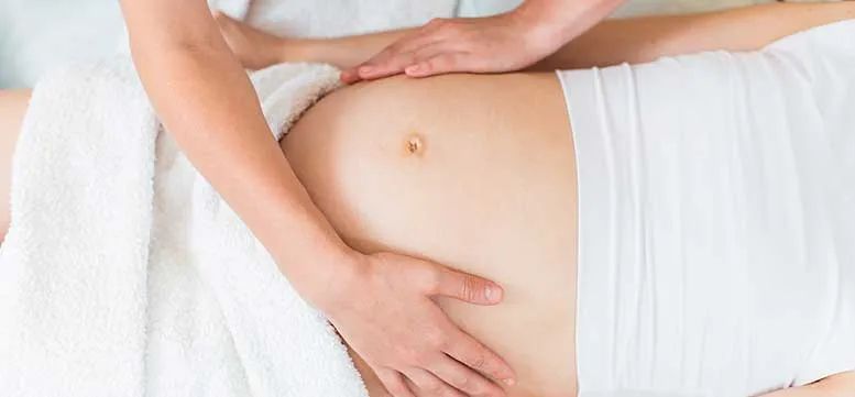 A pregnant woman is getting a massage at a spa.