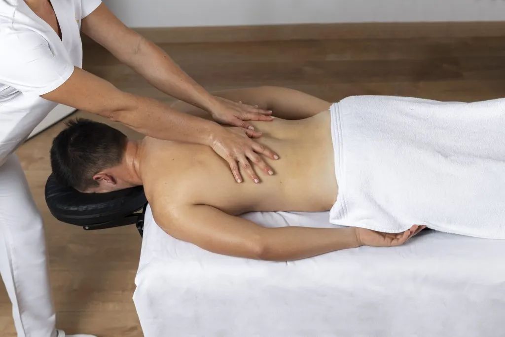 A man is laying on a table getting a massage from a woman.
