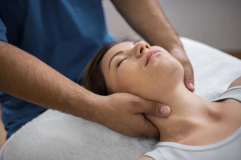 A woman is getting a neck massage from a man.