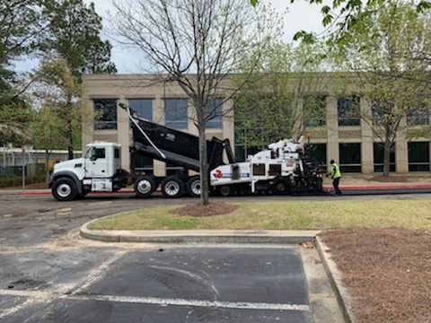A dump truck is parked in a parking lot in front of a building.