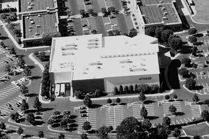 An aerial view of a mall surrounded by parking lots and trees.