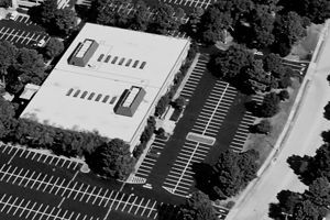 An aerial view of a building with a parking lot in front of it.