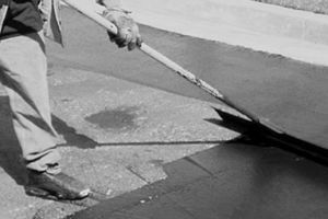 A man is painting a boat with a brush in a black and white photo.