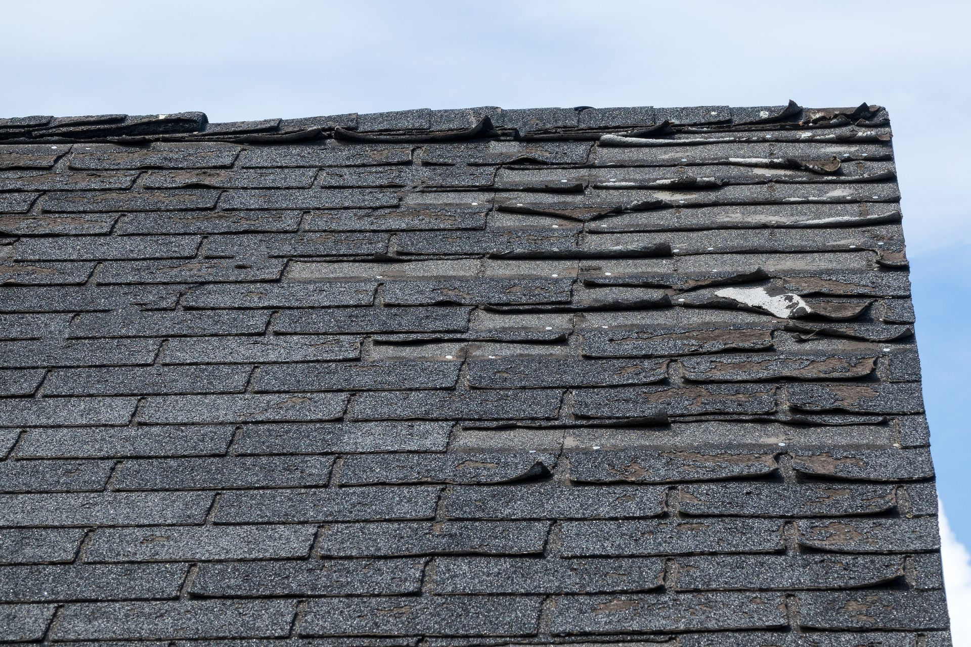 A close up of a roof with a lot of shingles missing.