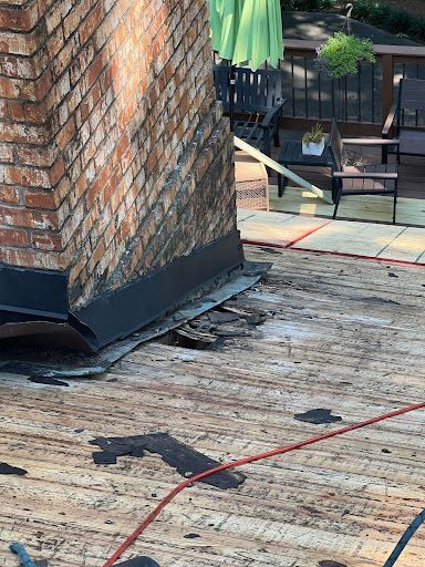 A brick chimney on a roof that is being repaired