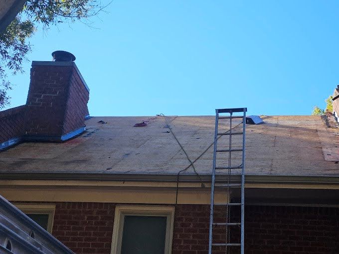 A ladder is sitting on the roof of a brick house