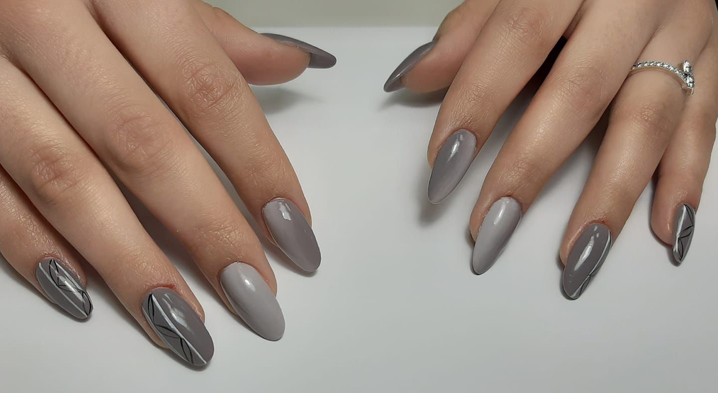 Un primo piano delle unghie di una donna con smalto grigio.