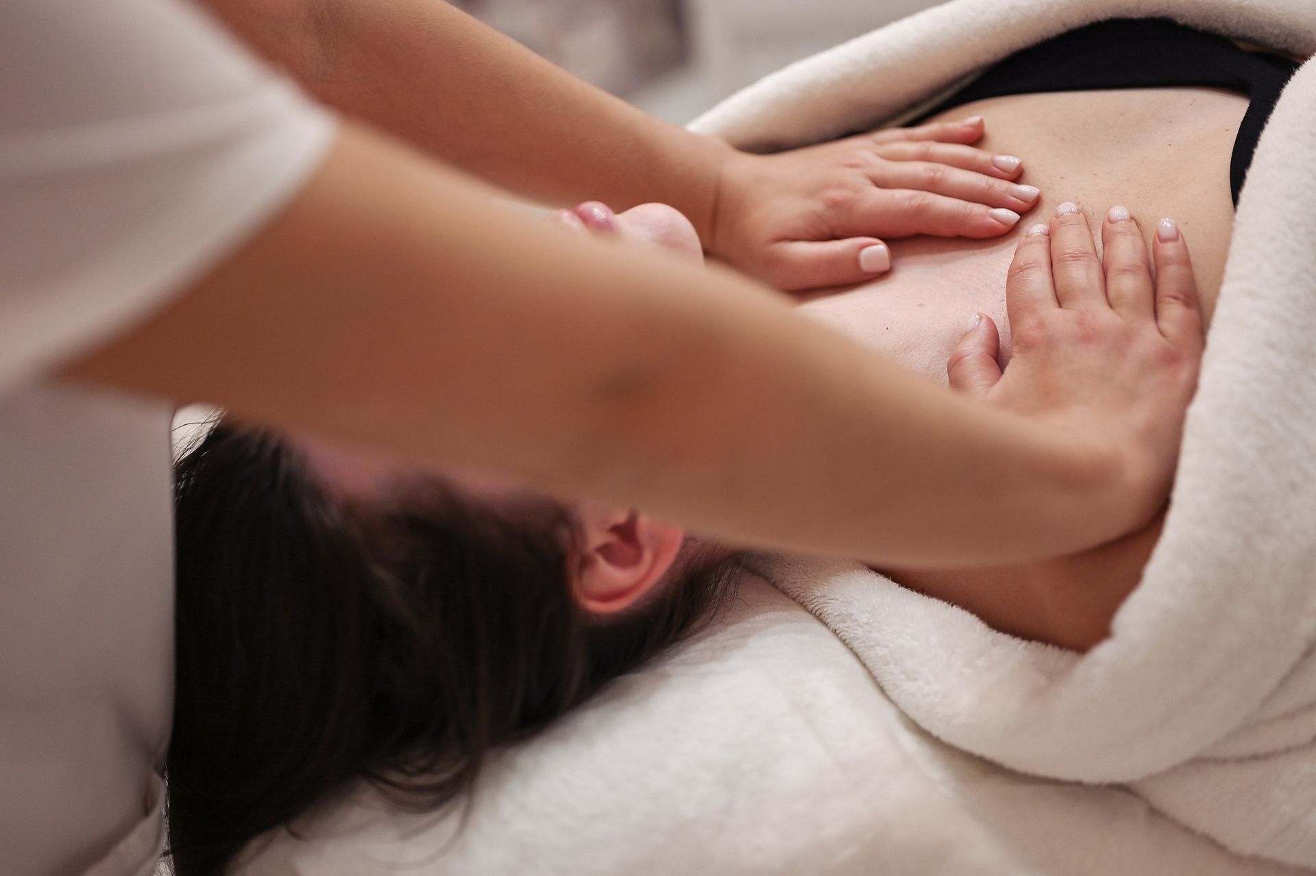 Una donna è sdraiata su un letto e riceve un massaggio.