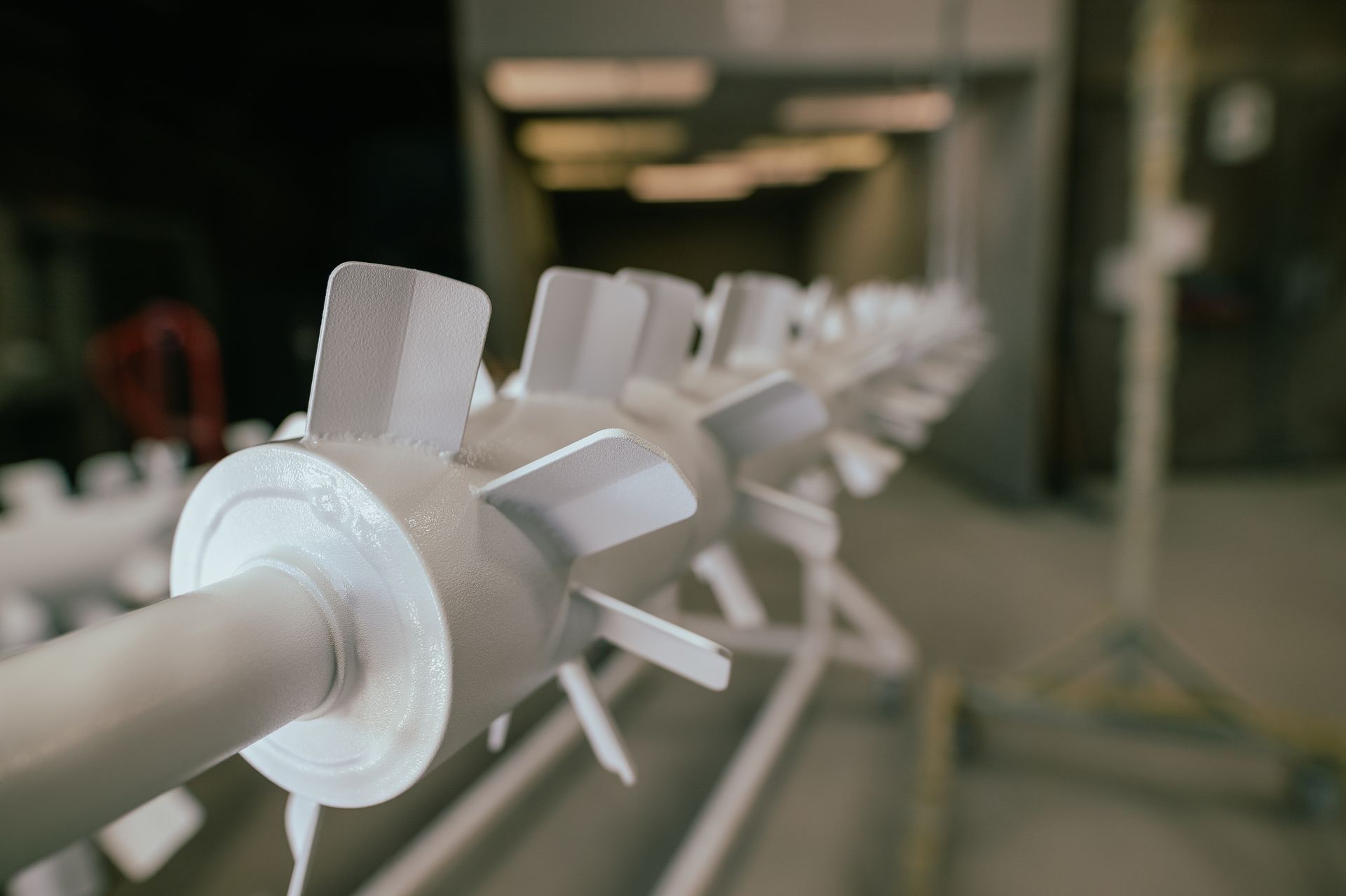 White metal fan blades on a rack in a factory setting.
