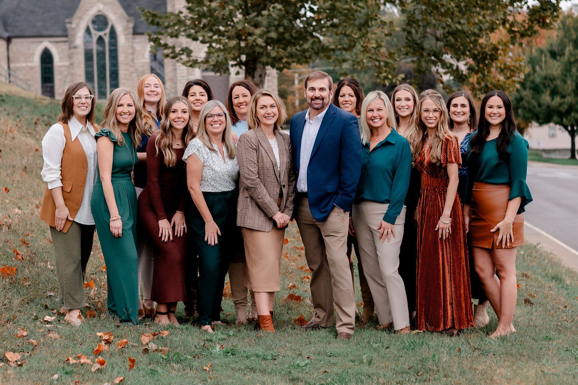 Six women posing on outdoor steps, building background. Variety of outfits, smiles.