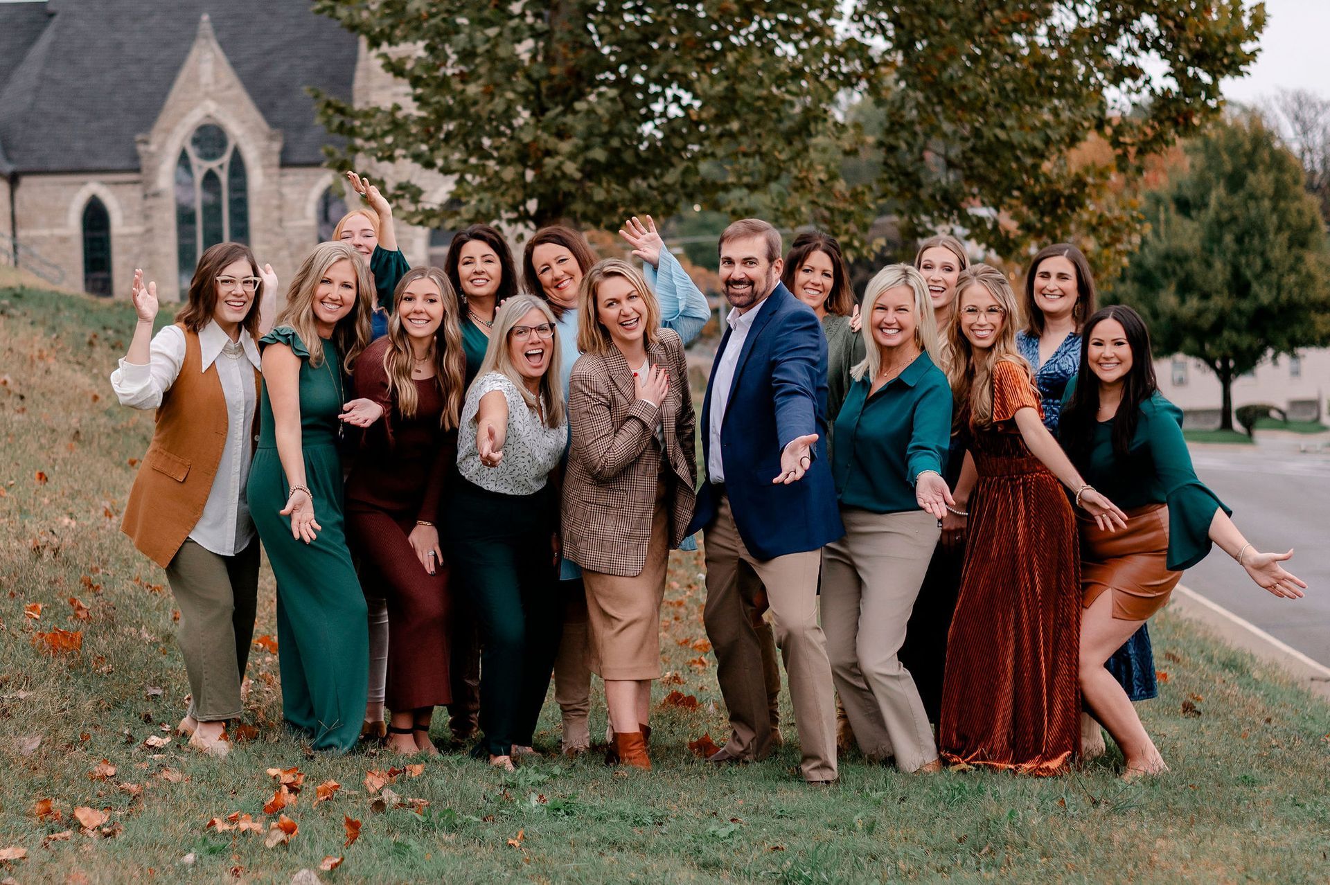 Group of people posing for a photo in front of a brick building with awnings.