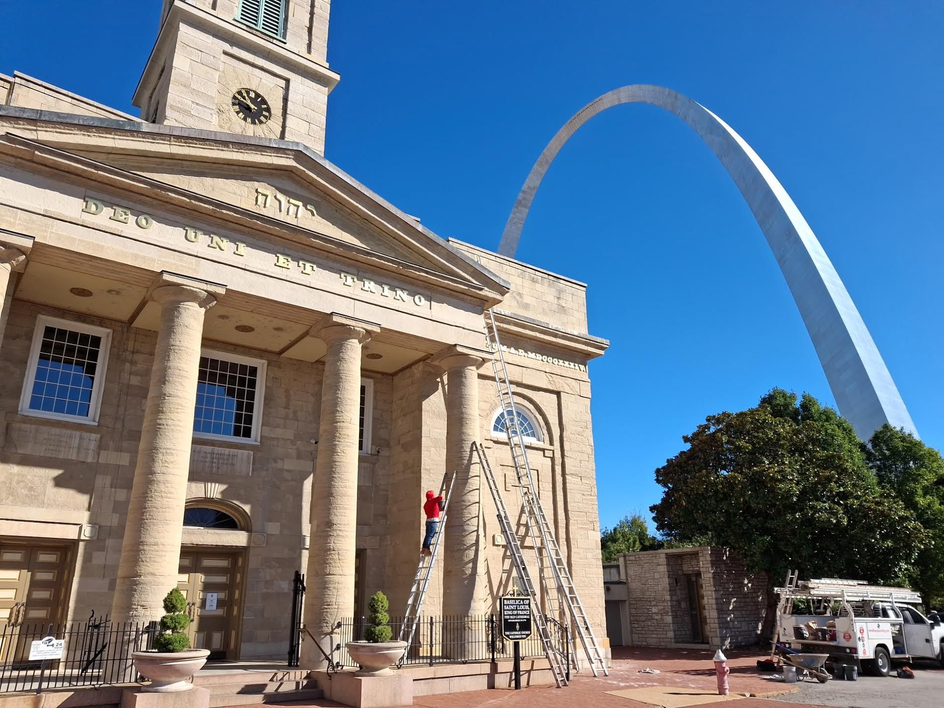 Historic building with columns, St. Louis Arch visible in background on a sunny day.