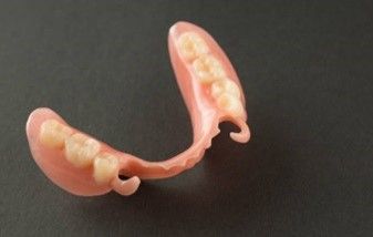 A close up of a denture with teeth on a black surface.