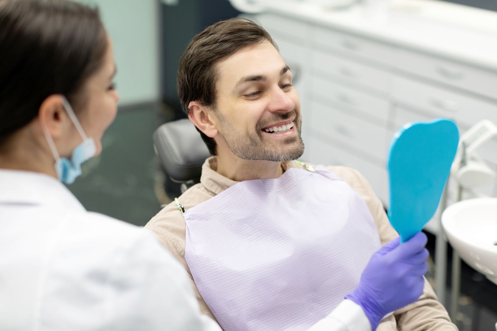 Happy man looking at mirror after teeth treatment Happy man looking at mirror after teeth treatment