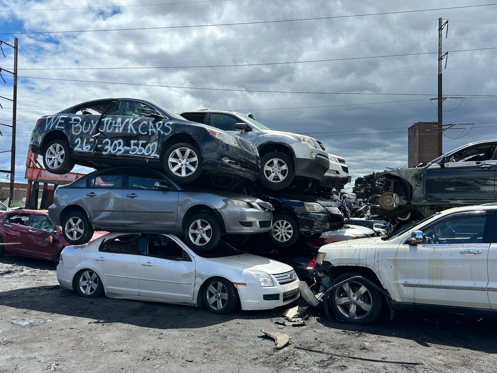 A bunch of cars are stacked on top of each other in a parking lot.